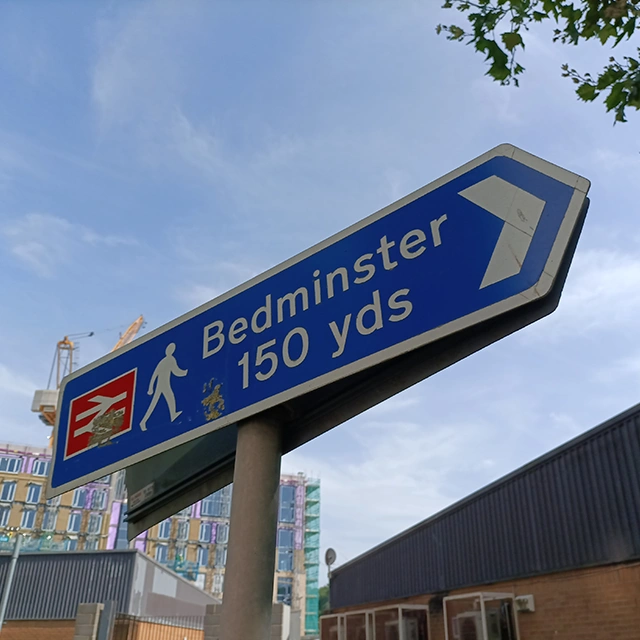 Sign pointing to Bedminster station 150yds away. In the background is the Bedminster Green construction site.